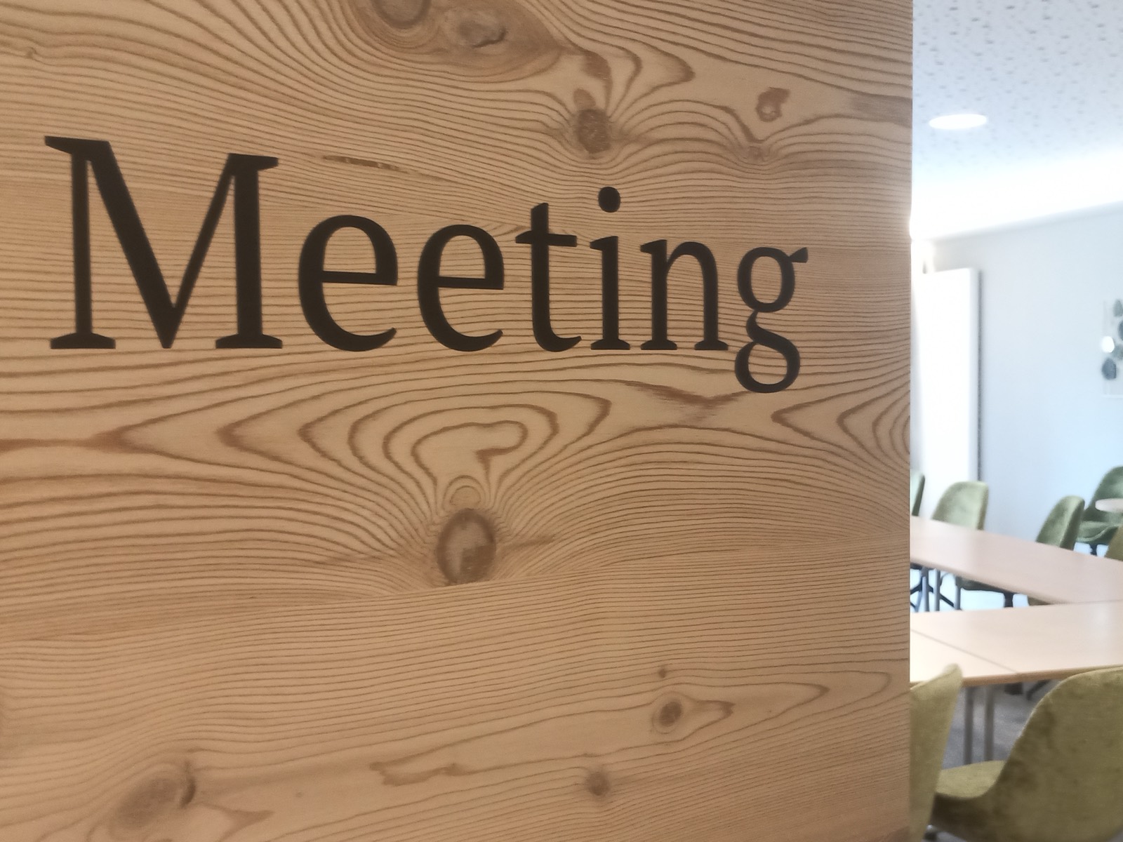 Scritta Meeting in effetto satinato davanti a una sala riunioni